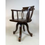 An early 20th century revolving desk chair with leather seat with studded finish. Repair to back,