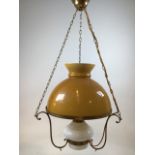 A hanging oil lamp with glass shade and reservoir with brass chains and decorative brass brackets