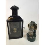 A black wall hung oil lantern with chimney vent and side opening door together with a small green