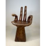 A solid wood seat in the form of a hand.