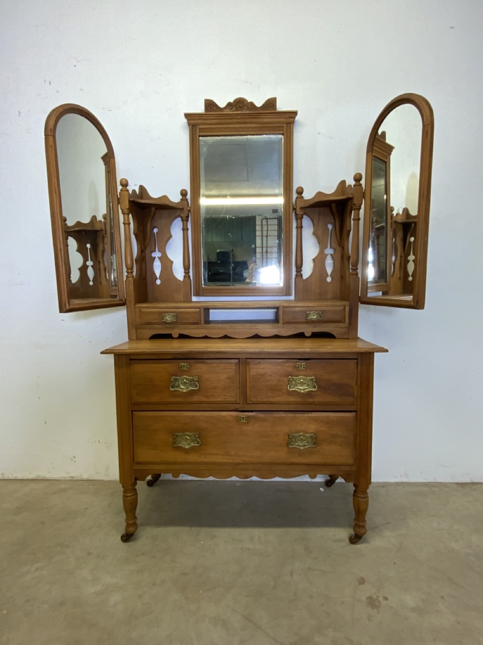 A decorative 20th century dressing chest with three drawers on ceramic castors. Triple mirrored