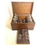 An oak cased 19th century portable liquor cabinet or cellerette. Six large decanters with gold