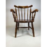 An early 20th century english country ash armchair with shaped arms, spindle back and penny seat.