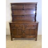 An Ercol style small dresser with two plate racks above sideboard base with two drawers and a