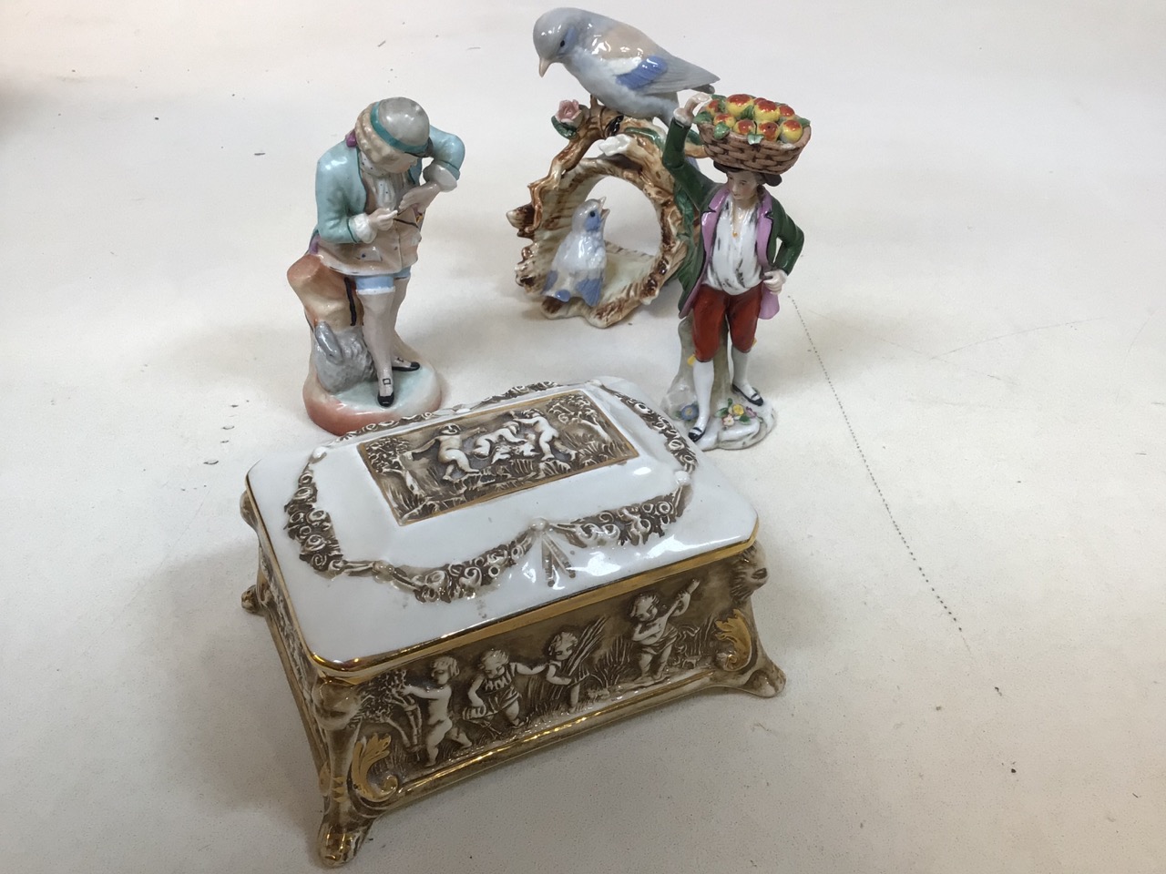 A Capodimonte footed lidded ceramic box decorated with children together with three decorative