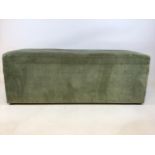 A large early 20th century pine ottoman with green fabric upholstery on small bun feet.