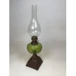 An oil lamp with green glass reservoir on decorative metal base Height 54cm