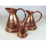 Three graduated copper jugs. Largest H:31cm