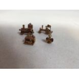 Four 9ct gold charms - railway interest. Includes a train in a station, two steam engines and a lamp