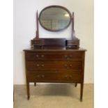 An inland dressing chest with oval bevelled mirror flanked by vanity drawers above three long
