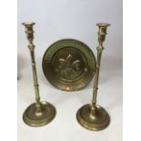 A pair of brass candlesticks Height 46cm together with a brass charger decorated with a fleur de