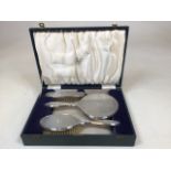 A boxed silver dressing table set with two brushes and a hand mirror. Retailed by Liangs