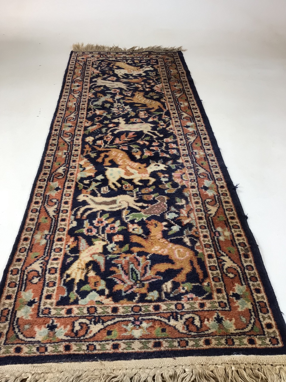 A vintage Persian wool rug with navy ground and hunting animalsW:46cm x H:137cm includes fringe