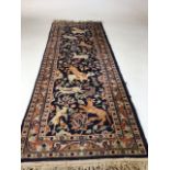 A vintage Persian wool rug with navy ground and hunting animalsW:46cm x H:137cm includes fringe