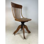 An stick back bentwood Edwardian oak swivel chair with leather seat and metal swivel mechanics, with