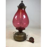 A very large early 20th century oil lamp with large cranberry shade and clear glass chimney.