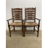 A pair of oak ladder back wicker seated carver arm chairsW:57cm x D:52cm x H:110cm