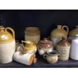 A large collection of stoneware flagons, pots and a teapot