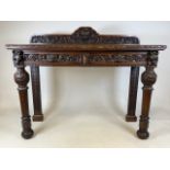 A Victorian heavily Carved oak hall table with green man central detail and carved green man cup