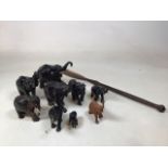 A collection of ten wooden elephants, some ebony, together with a wooden spear. Length of spear