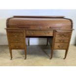 An Edwardian roll top desk with large central drawer flanked by brushing slides above three pedestal