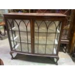 An Edwardian glazed bow front bookcase with lined shelves, ball and claw feet, glazed side panels