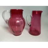 Two early 20th century cranberry jugs with clear glass handles.
