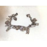 A silver charm bracelet hung with seventeen novelty charms including a windmill. Length of