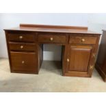A modern knee hole desk with three drawers flanked by cupboard and two drawers. W:142cm x D:64cm x