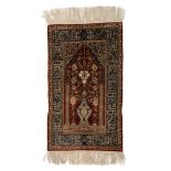 An Oriental silk on silk Hereke rug, decorated with a flower vase, the details finely brocaded with