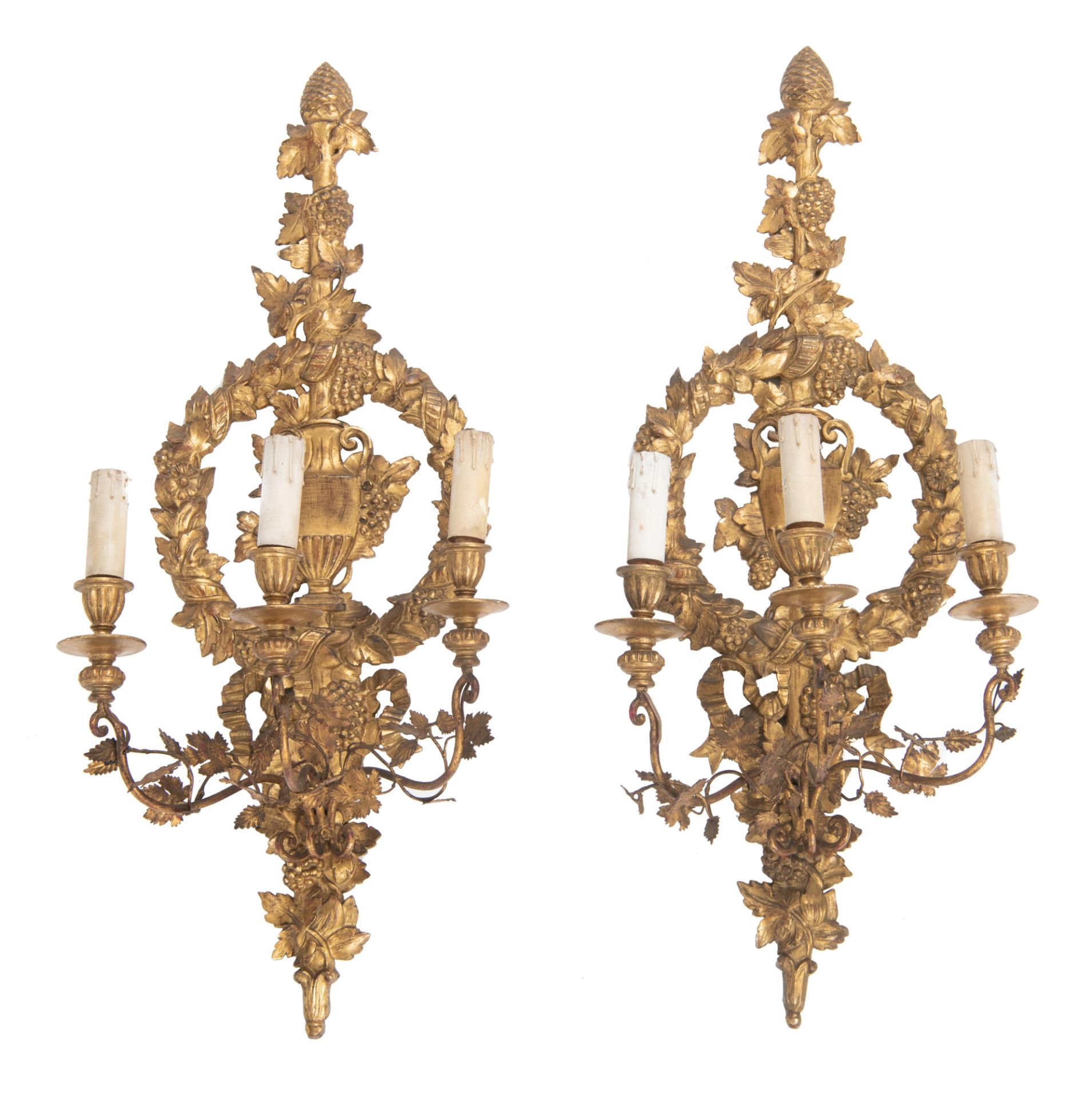 A pair of Baroque style carved and gilt wooden wall lights with floral decorated brass arms, richly