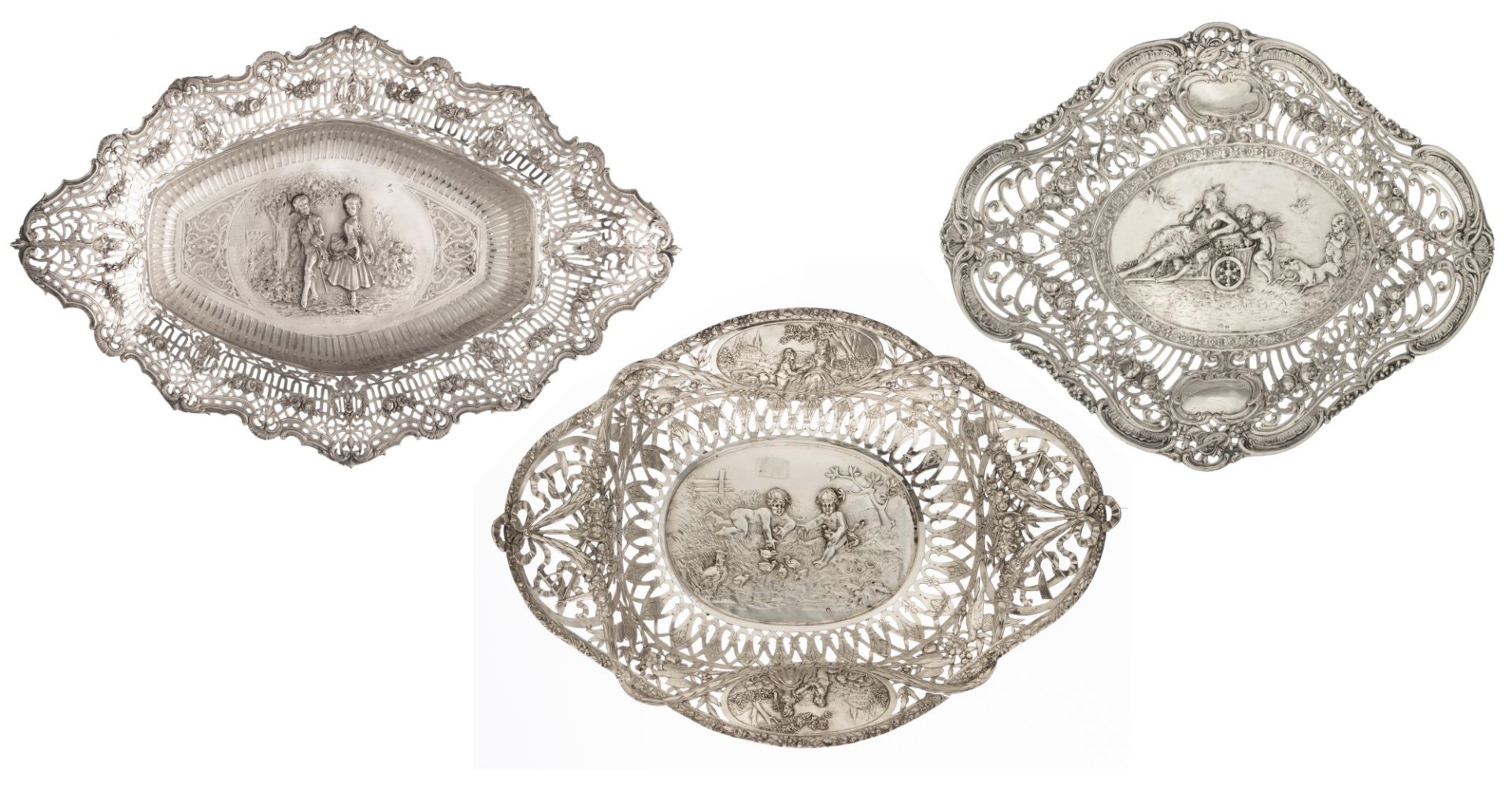 A collection of three silver chargers with ornate repousse pierced work, the well depicting playing