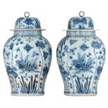 A pair of Chinese blue and white covered vases, decorated with carps in a pond, with a Kangxi mark,