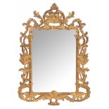 An Italian type wall mirror with a richly and baroque carved, gilt and patinated wooden frame, 78 x