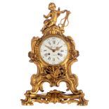 A Rococo Revival ormolu bronze cartel clock, decorated with a trophy and a putto holding a lyre on t