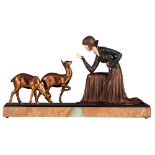 An Art Deco chryselephantine sculpture of a lady feeding deer, patinated spelter and ivory on an ony