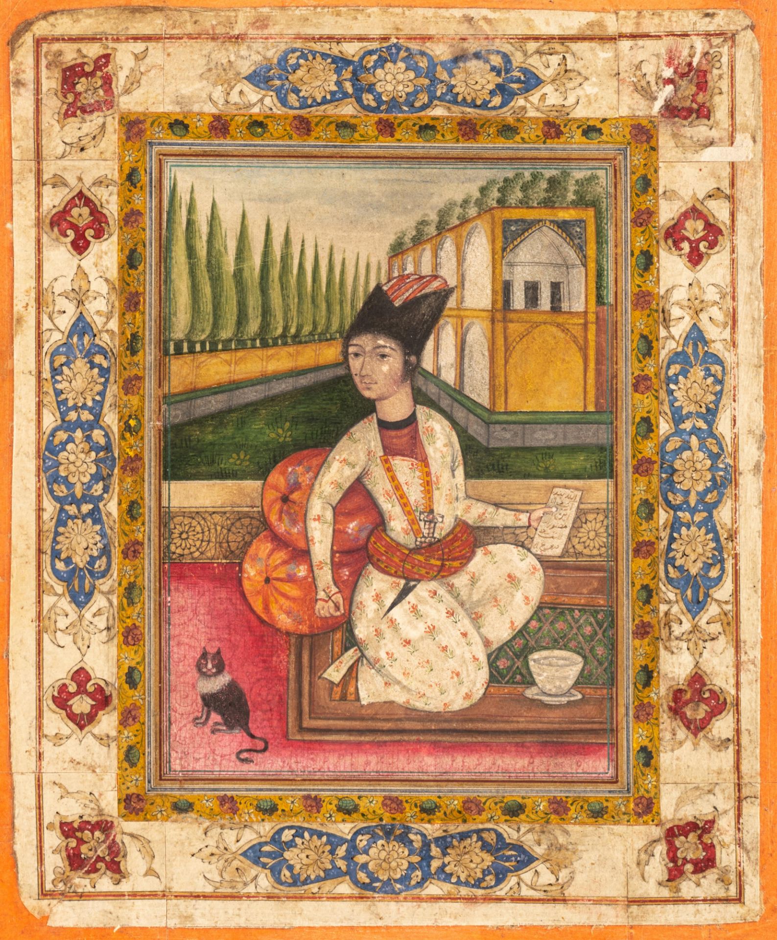 A Persian 19thC gouache painting on paper depicting an elegantly dressed Qajar youth holding a pen a