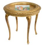 A finely carved gilt wooden round side table, with on top a hand-painted Vienna porcelain plaque dep