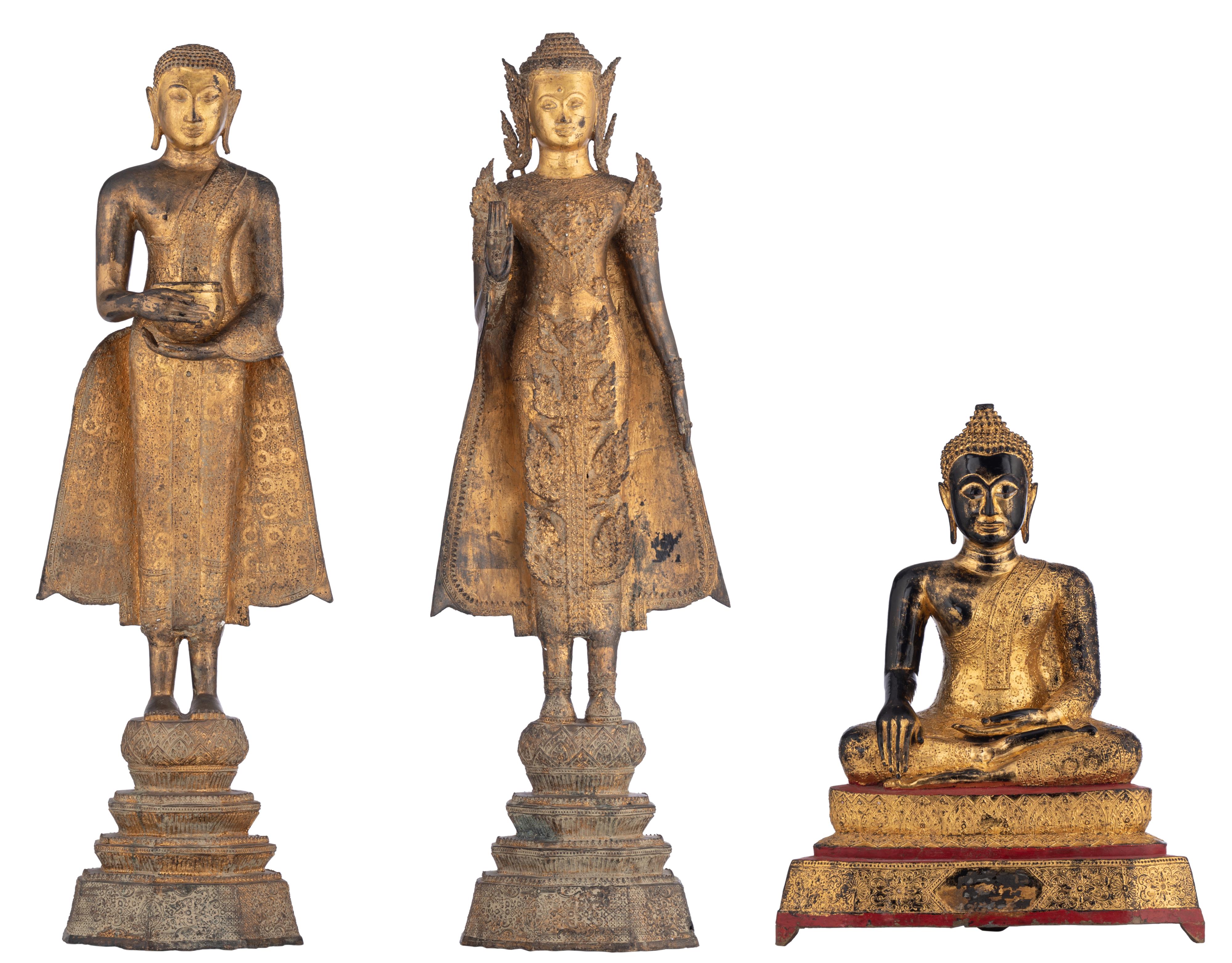 Two gilt bronze standing Buddha and a lacquered and gilt wood seated Buddha, Thailand, Tallest H 121