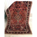 9 (L 249) Rug / carpet - a hand made wollen carpet with wine red ground with central cross and