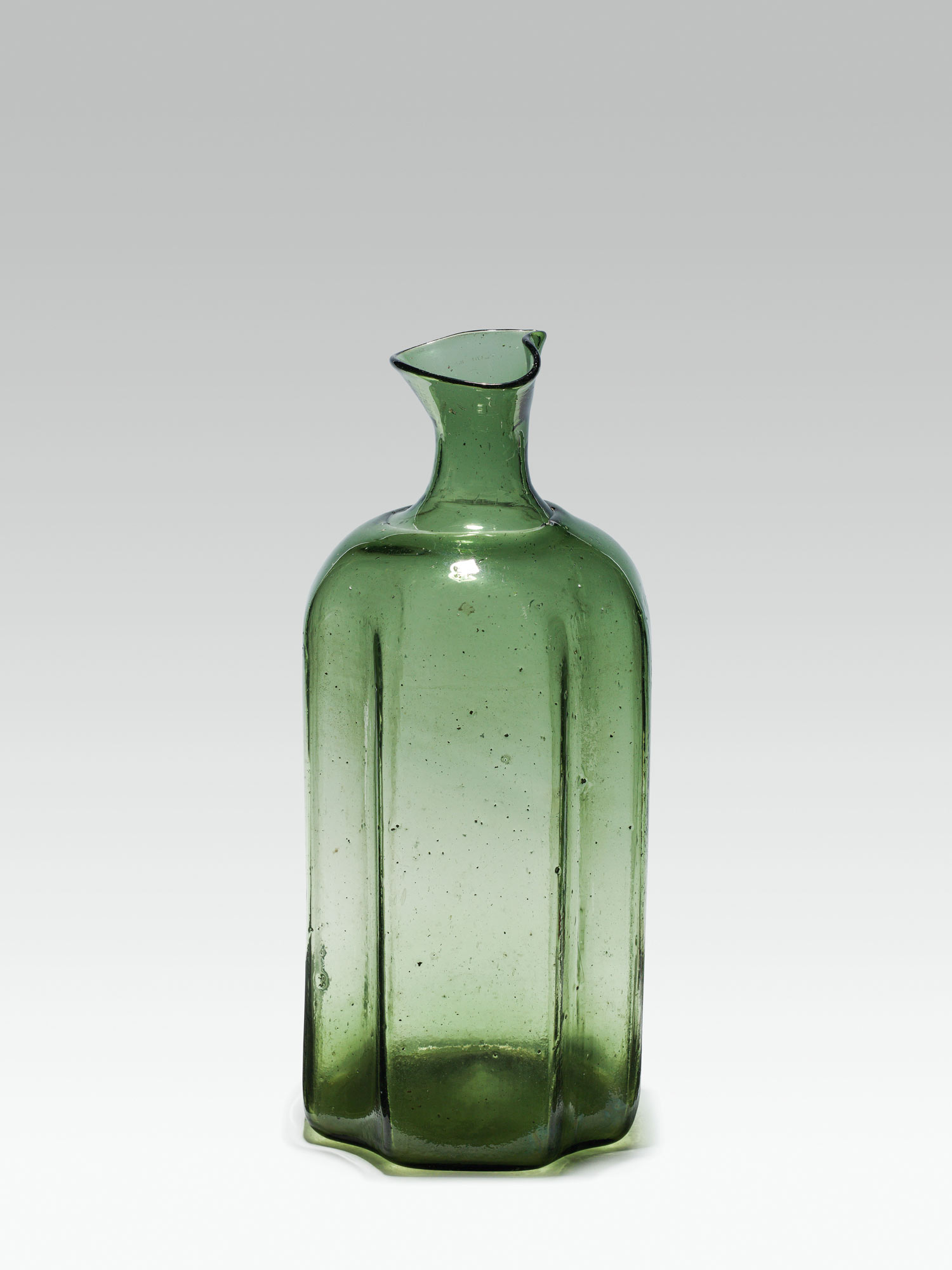 Large bottlegreen glass; pontil mark at the base; cinched concave edges, rounded shoulder, high