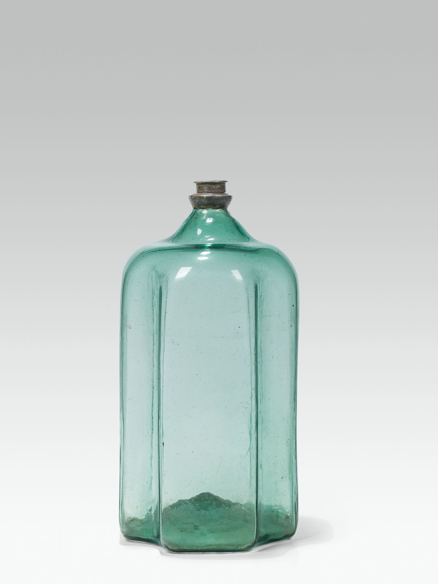 Large bottlegreen glass; pontil mark at the base; cinched concave edges, lightly rounded shoulder;