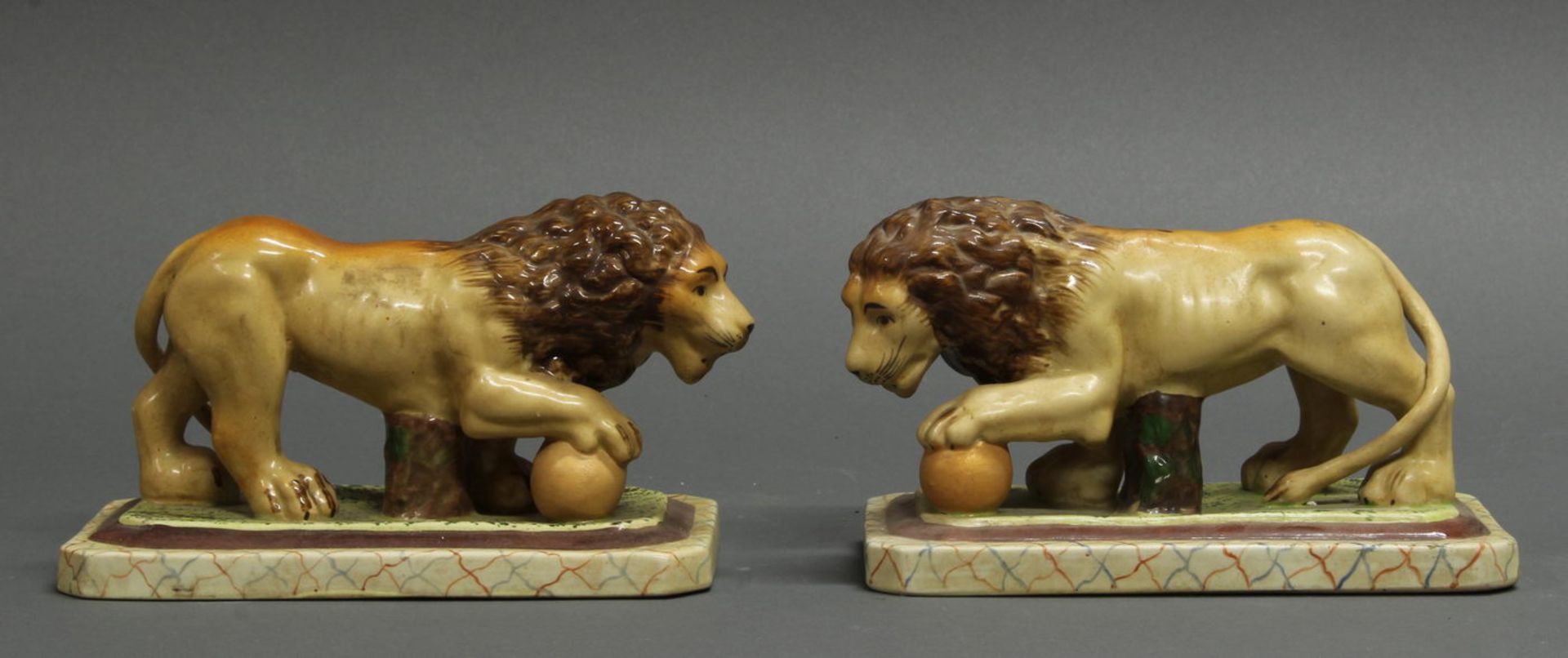 Paar Löwen, mit Ball, Porzellan, polychrom bemalt, gesockelt, 10 cm hoch