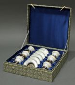 6 Mokkatassen mit Untertassen, Silber 925, weißer Emaildekor mit goldenen Lilien, Porzellaneinsätze