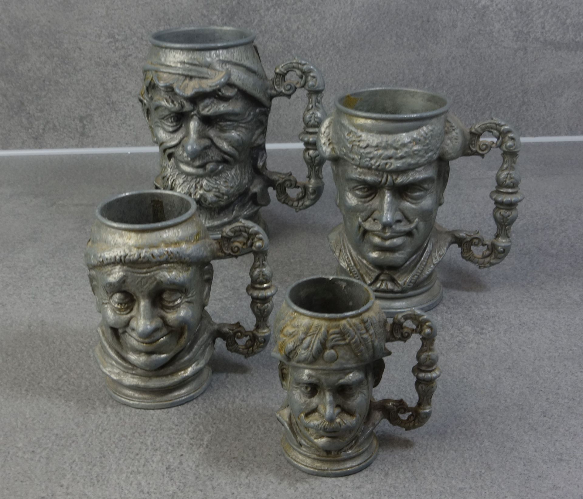 FOUR FIGURAL METAL JUGS WITH CHARACTER HEAD