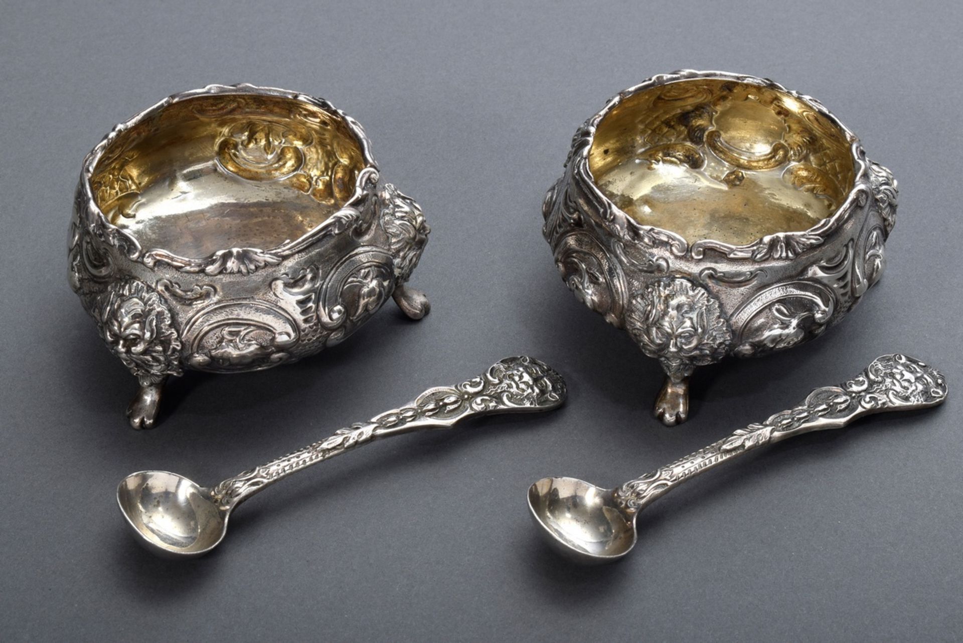 Pair of English salt cellars in rich relief on three feet with sculpted mascarons and supplemented 