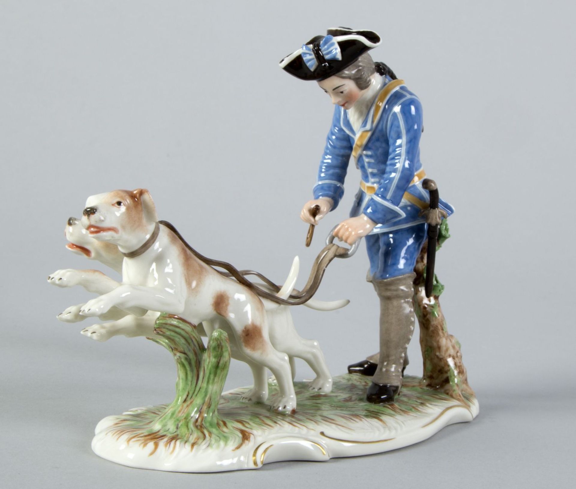 Piqueur mit 2 Hunden aus der "Blauen Jagd"Polychrome Bemalung. Goldstaffage. Gepresstes Raute