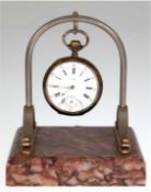 Taschenuhrenständer mit Uhr, über roter Marmorplinthe bogenartiges Metallgestell mit eingehängter T