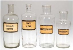 4 diverse Apothekerflaschen, farblos, Etiketten mit lateinischer Bezeichnung, H. 18,5 bis 22 cm