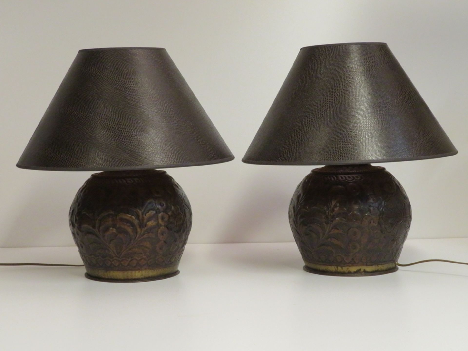 2 Tischlampen, runder reliefierter Messingfuß floral getrieben, Schirme in brauner Schlangenlederop